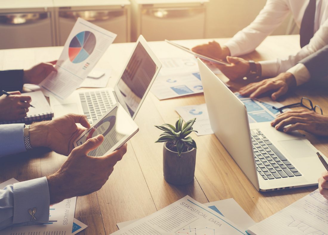 Groupe de personnes travaillant sur ordinateur et tablette autour d'un bureau