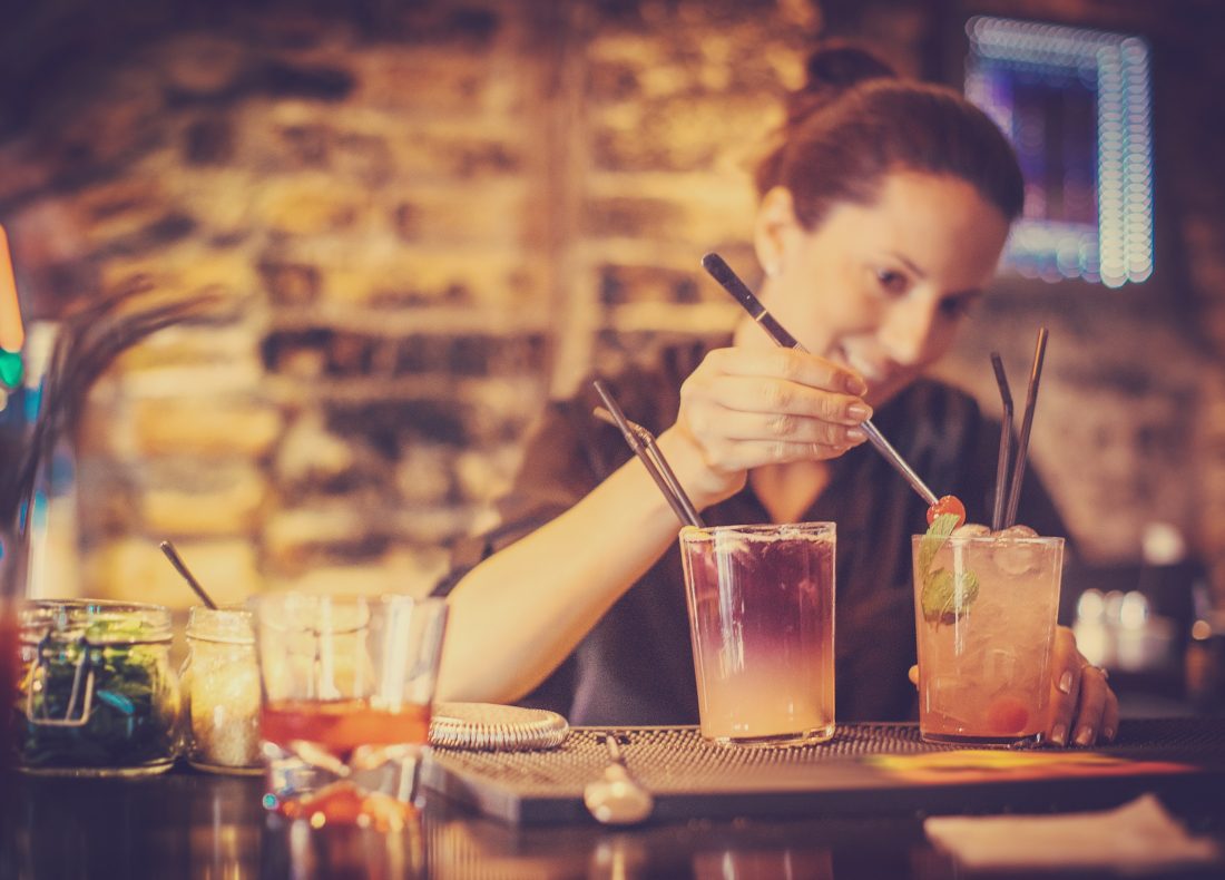 Portrait d'une barmaid préparant un cocktail au bar de l'hôtel Suitcase Hospitality