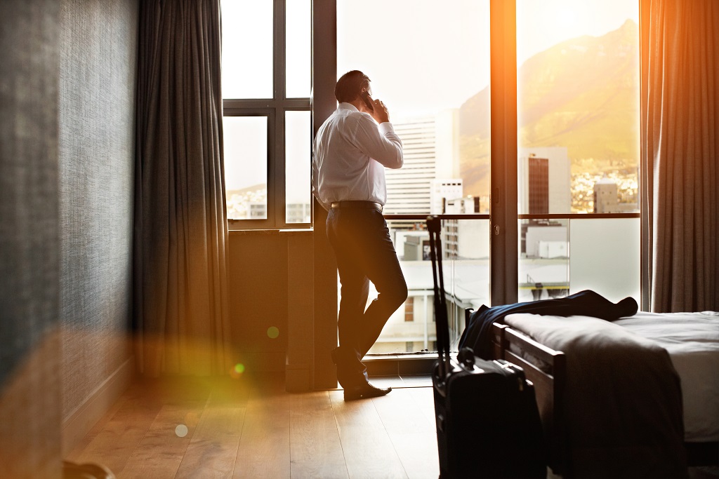 Homme d'affaires parlant au téléphone depuis la fenêtre de sa chambre d'hôtel